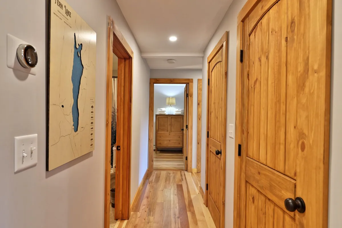 The image captures a bright hallway with wooden flooring, a map adorning the wall, and sturdy wooden doors leading to other interior rooms. The atmosphere is welcoming and practical, suggesting a space ideal for stowing away seasonal gear or outdoor clothing, and acting as a transitional entry or mudroom.