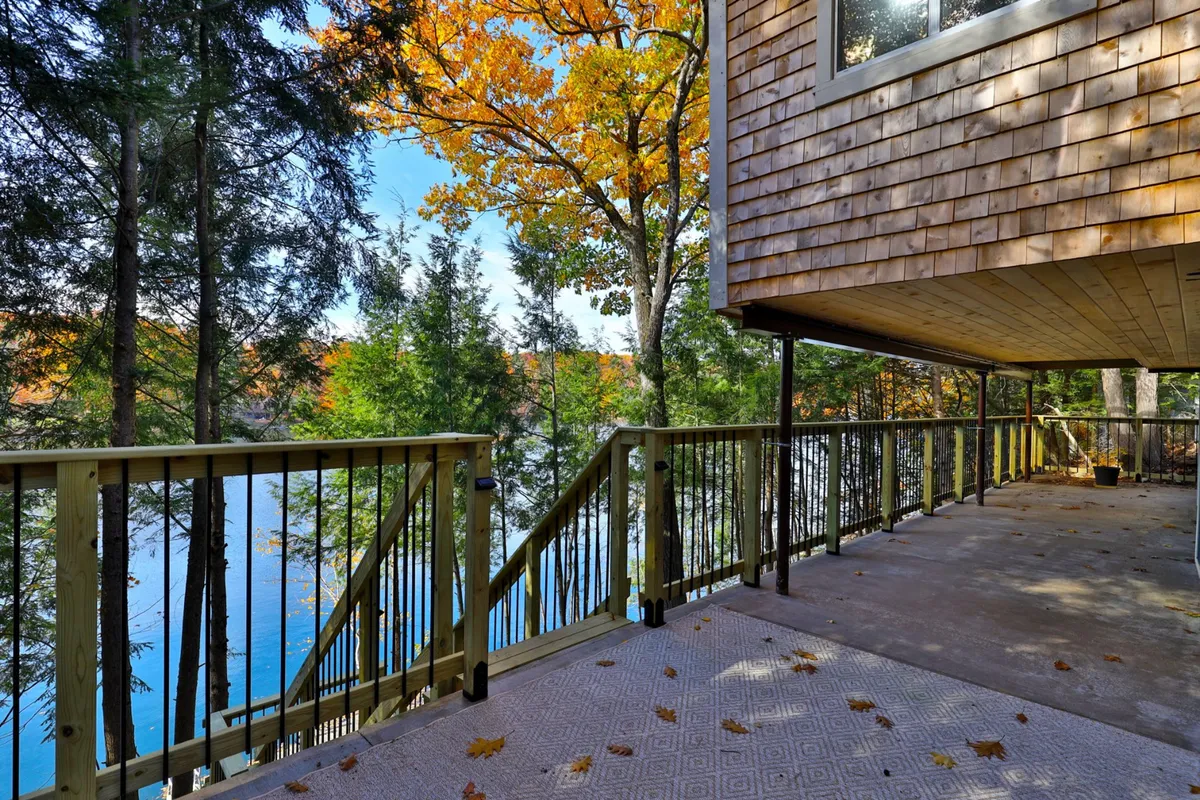 A tranquil view of the lake framed by colorful autumn leaves and a wooden deck. The image exudes peacefulness and showcases direct lake access, emphasizing the seamless connection between indoors and the natural world.