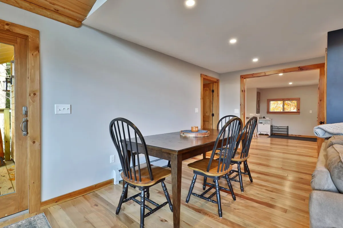A dining area with a sturdy wooden table and chairs, an open entryway, and ample space for group gatherings. The mood is warm and welcoming, inviting memorable family meals or celebratory dinners.